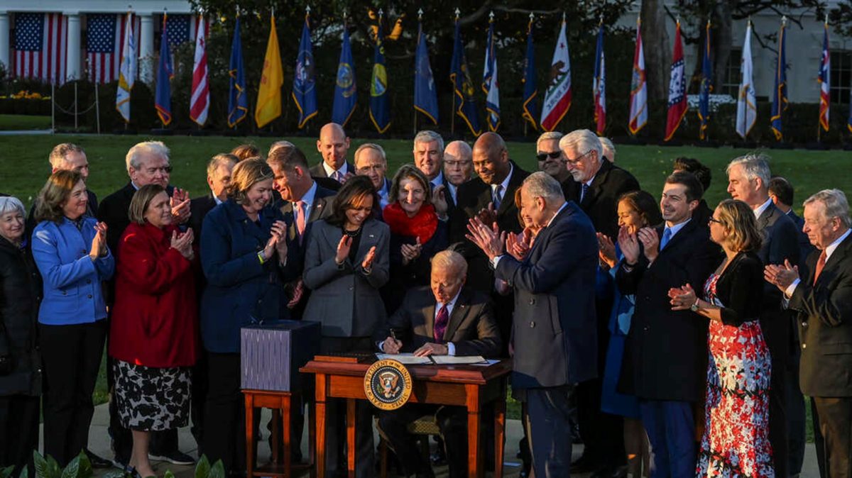 President Biden signs the Infrastructure Investment and Jobs Act as he is surrounded by lawmakers and members of his Cabinet during a ceremony on the South Lawn at the White House on Monday. Kenny Holston/Getty Images